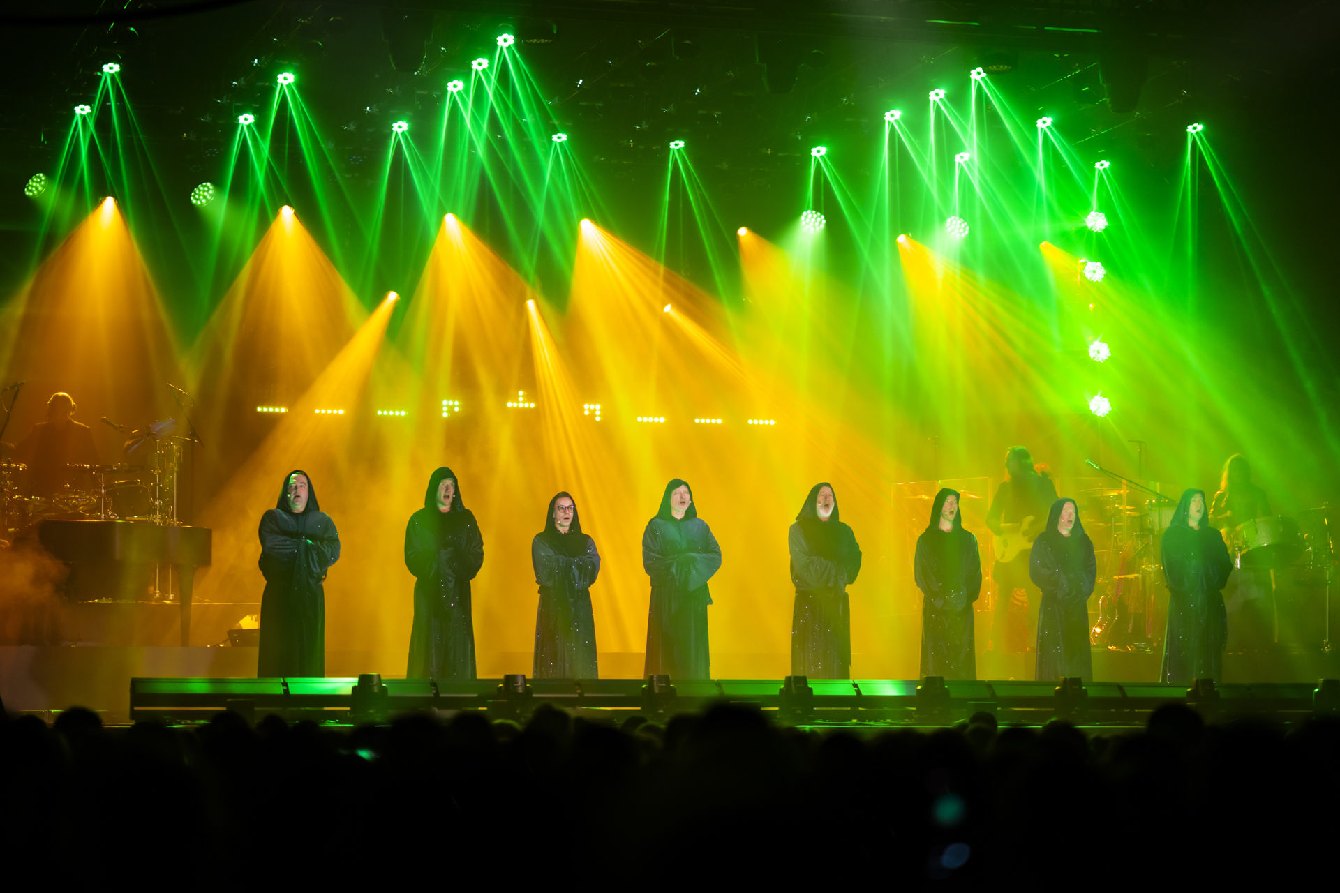 Sbor Gregorian na pódiu pod zelenými a zlatými světly při předchozím pražském koncertu